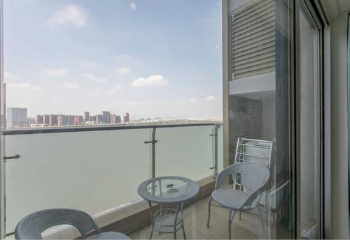 Balcony with chairs, table, and view of the city skyline at day