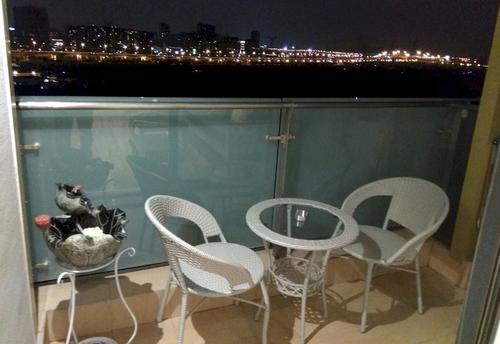 Balcony with chairs, table, and view of the city skyline at night