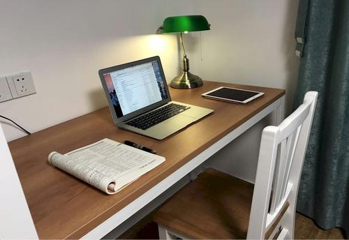 Wooden desk and chair with Macbook Air, iPad, pen, booklet and lamp